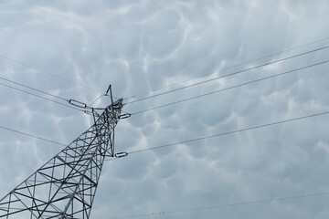 High voltage pole against a backdrop of billowing storm clouds.