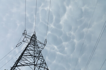 A steel power transmission pole against a backdrop of storm clouds.