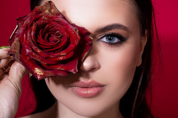 Fototapeta na wymiar Young beautiful stylish sensual woman with blue eyes and rose. Woman with red lips and rose flower. Fashion beauty portrait on studio background.