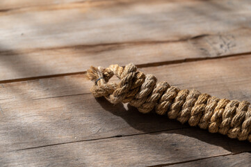 Coiling a natural rope against a wooden background. Rough, cracked boards. Natural lighting.