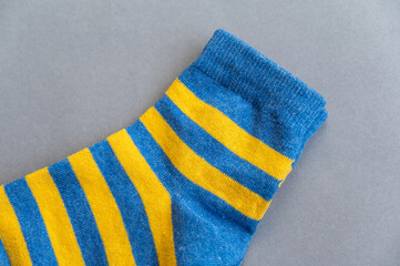 Blue and yellow socks against a gray background. A pair of bright colorful striped socks