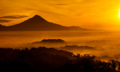Beautiful Scene of Merapi Merbabu Mountain at Sunrise time from Punthuk Setumbu. In front of the mountain there is silhouette of Borobudur temple. 