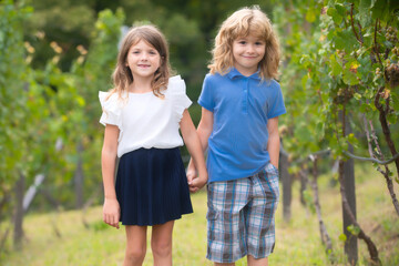 Cute little children walking outdoors. Portrait of two happy young kids at the spring park. Cute lovely boy and girl in backyard. Sister and brother walking in garden.