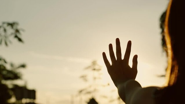 Hand, child dream to sun. Sunset between hands of child girl. Teenage girl dreamily stretches out her hand to sun, rays of sun make their way through her fingers. Hand of happy girl reaches for sun.