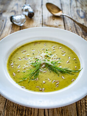 Cream zucchini soup with sunflower seeds and fresh dill on wooden table