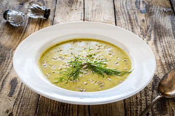 Cream zucchini soup with sunflower seeds and fresh dill on wooden table
