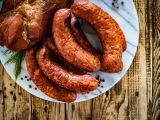 Smoked sausages and ham on wooden table