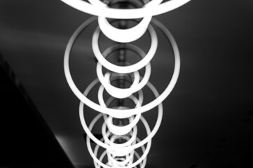 blurred hanging lamp bulb in the form of rings. blur abstract lighting modern pendant electricity round lamps chandelier glowing gray dim light inside a room. tinted in black and white