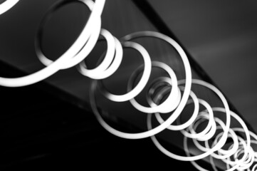 blurred hanging lamp bulb in the form of rings. blur abstract lighting modern pendant electricity round lamps chandelier glowing gray dim light inside a room. tinted in black and white