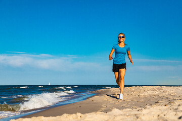 Fototapeta na wymiar Young woman running, jumping on beach
