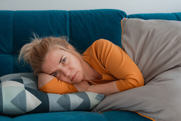 depressed mature woman lying sofa with her arms around herself, covering her head with hands,...