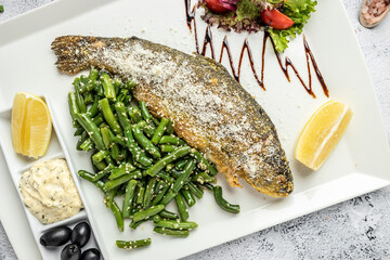 Fish dish roasted trout with parmesan, lemon and vegetables on a light background. Restaurant menu, dieting, cookbook recipe. top view