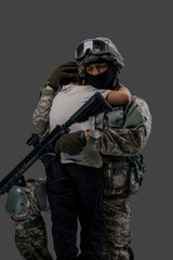 Portrait of professional serviceman dressed in camouflage clothes hugging little boy.