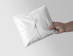 White plain wrapped gift wrapping tissue paper holding in hand against white background. 