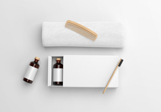 White blank Hotel Amenity Box with towel and wooden comb and toothbrush on a plain background. 