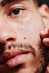 Close-up of bearded mixed race man applying protected face cream on his skin