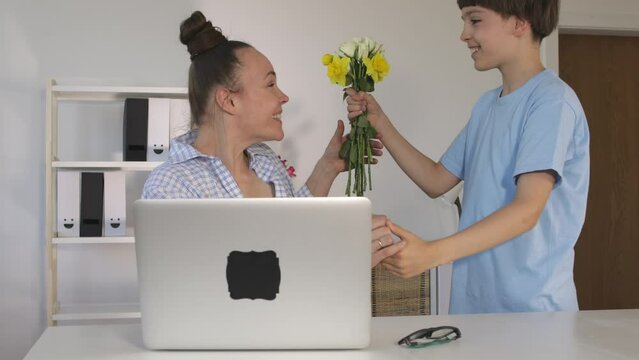 Son of 12 years presents a bunch of flowers to the mother