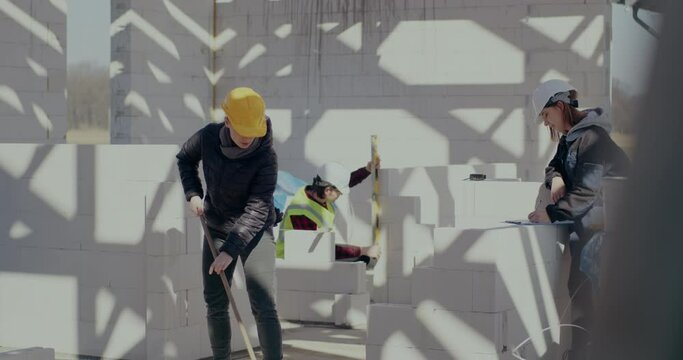 Female worker brooming near coworkers at construction site