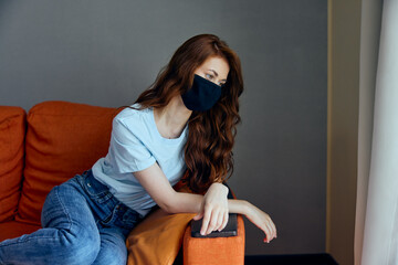 portrait of a woman in black protective masks sitting on the couch at home stay home concept