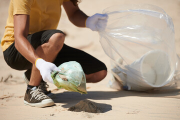 Volunteer collecting garbage left by tourists on sandy beach