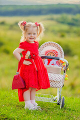 girl with a toy stroller walks in nature