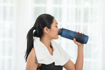 Athletic Healthy Asian young woman in sportswear drinking water after workout exercise at...