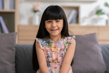 Portrait of asian children smile looking at camera at home.Happiness Little toddler laughing with white teeth on couch in cozy home.Healthy kid concept