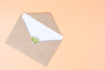 Opened paper envelope with white paper empty note with tiny white blossoming flowers inside, mock up with copy space.Vertical photo.Concept of spring coming, holidays, good news and love emotion