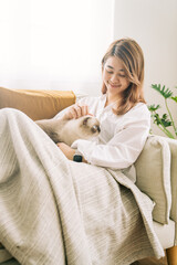 Young girl with happy soft cuddly white cat lying in lap enjoying and purring at home warm and cozy atmosphere