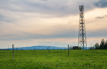 Mobile transmitter tower on spring meadow with sunset cloud sky. Czech landscape