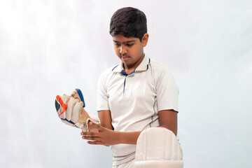 Portrait of young Indian boy wearing hand gloves and getting ready for Cricket game