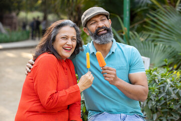 Happy indian senior couple enjoy ice cream in summer, mature people have fun, retirement life. ...