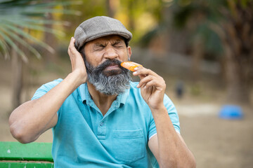 Indian senior man have sensitive teeth gum problem with ice cream  Mature adult pain in mouth,...
