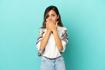 Young woman over isolated blue background covering mouth with hands