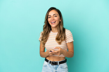 Young woman over isolated blue background surprised and sending a message