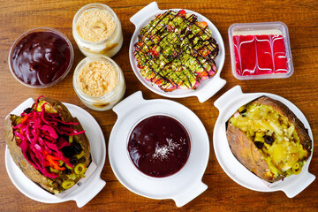 Top view of table scene with assorted take out or delivery foods. Meat and chicken doner kebab sandwich, wrap and on the plate with vegetables and sauce, including fries and pickles.