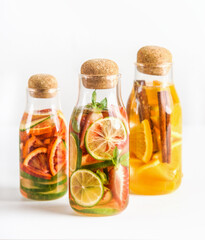 Infused water bottles flavored with various fruits at white background. Healthy lifestyle. Summer refreshing sugar free drinks. Front view.