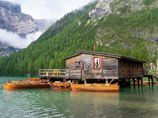 Lake Braies, Italy. Group of the traditional rowing boats docked to the wood house. Iconic location for photographers. Picturesque mountain lake in Dolomites. Wonderful nature contest. Alpine lake