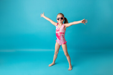 Funny happy child jumping in swimsuit and swimming glasses on colored background