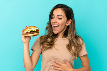 Young woman holding a burger over isolated background