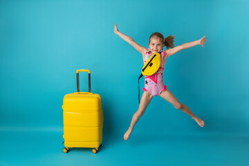 Funny happy child jumping in swimsuit and swimming glasses on colored background