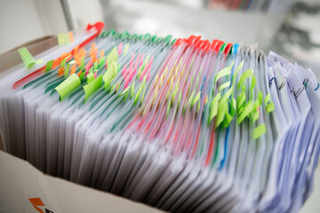 Stack of business report paper file on modern white office desk with bokeh background.