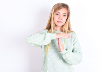 little caucasian kid girl wearing fashion sweater over blue background being upset showing a timeout gesture, needs stop, asks time for rest after hard work, demonstrates break hand sign