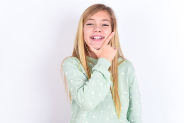 little caucasian kid girl wearing fashion sweater over blue background looking confident at the camera smiling with crossed arms and hand raised on chin. Thinking positive.