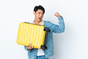 Chinese man over isolated background in vacation with travel suitcase