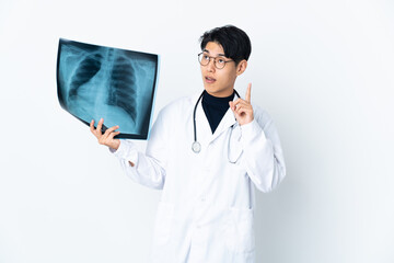 Young Chinese doctor man holding radiography isolated on white background thinking an idea pointing...