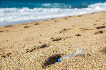 Garbage pollution of the planet. Empty plastic bottle on the beach sand. Consequences of human life