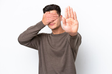 Naklejka premium Young handsome caucasian man isolated on white bakcground making stop gesture and covering face