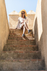 young tourist woman sitting on stairways enjoying a visit at the tower of the old Kasbah on a sunny day