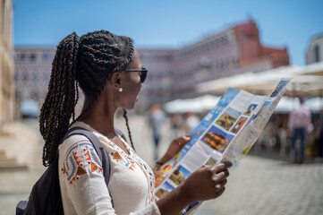 Young tourist woman viewing a map in an old town square in Spain visiting a European city
